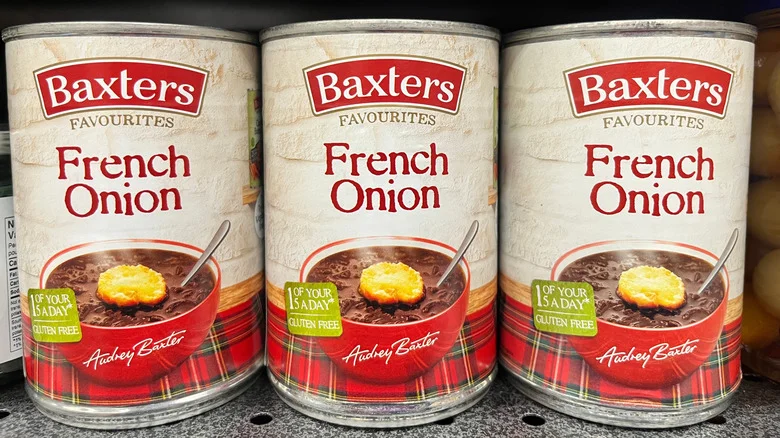 Cans of Baxters French onion soup on display on a grocery store shelf.