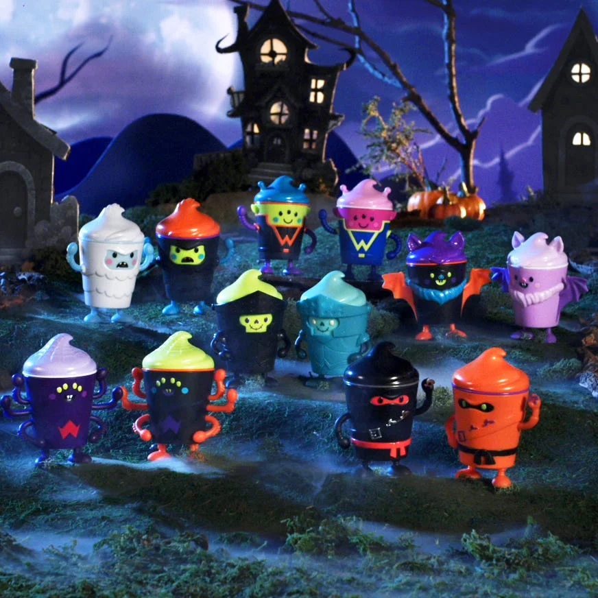 Colorful spooky characters and haunted houses set against a moonlit night sky, creating a Halloween-themed scene.