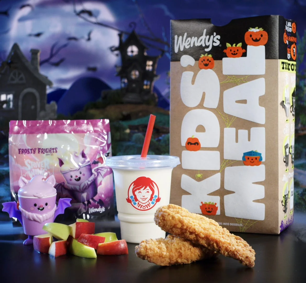 Wendy's Kids Meal featuring chicken nuggets, fruit, Frosty, and a Halloween-themed cup on a spooky backdrop.